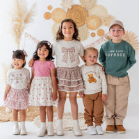 Five children standing together in front of a decorative floral backdrop