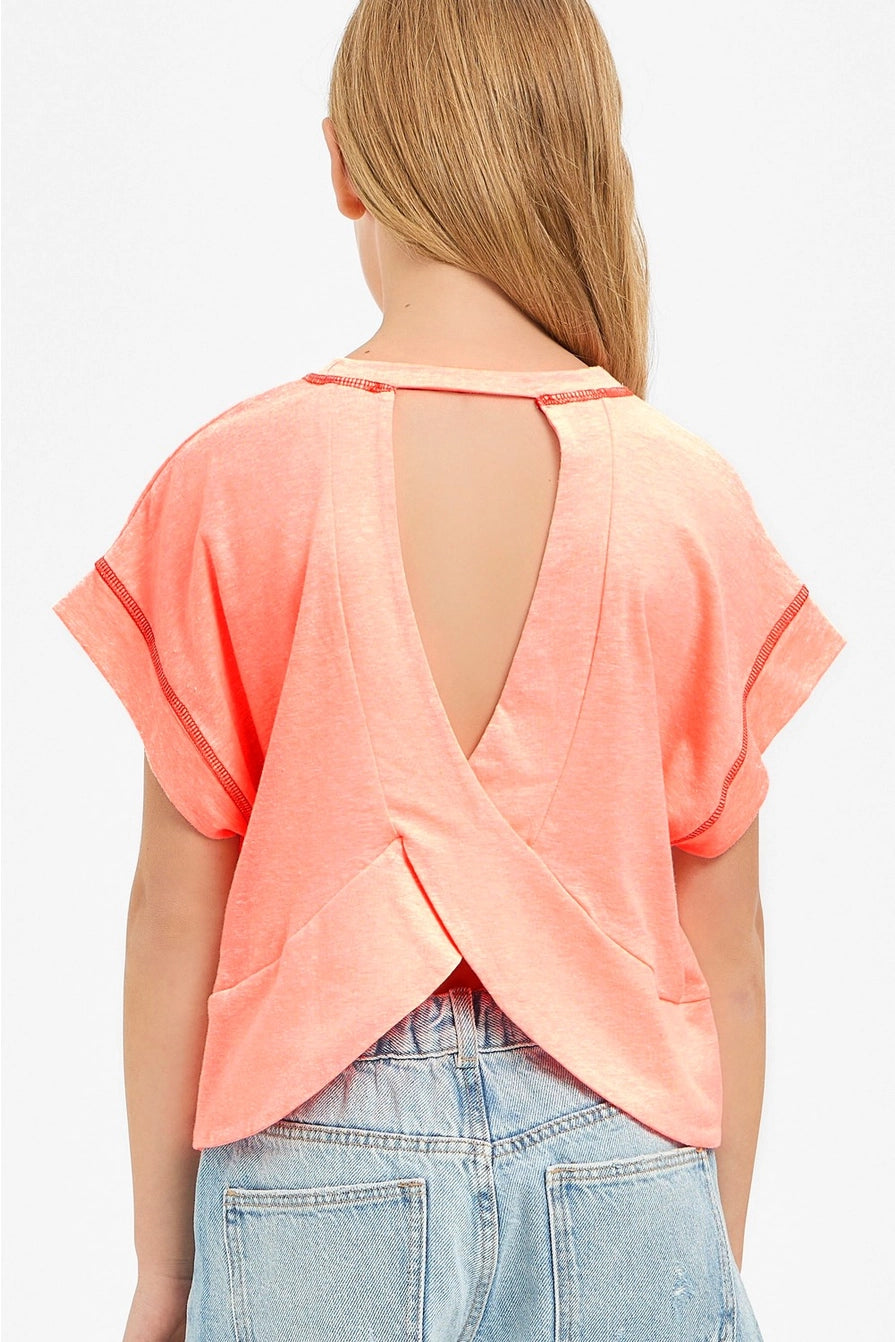 Girl wearing a peach-colored open-back top with denim shorts on a white background