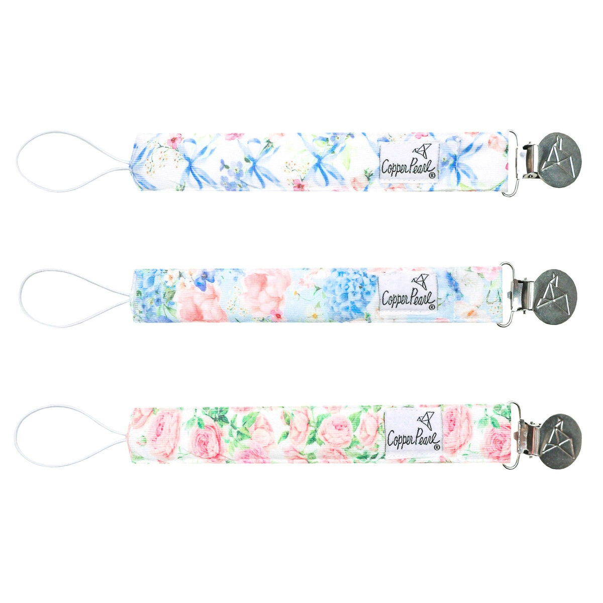 Three floral-patterned pacifier clips with metal clasps on a light 